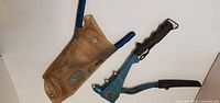 Both riveting tools: one blue rivet gun, one blue-handled tool in pouch