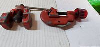 Both red pipe cutters side by side on surface