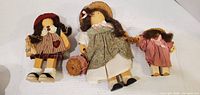 Front view of three wooden dolls showing outfits and accessories