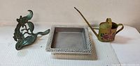 All three metal items: cast metal bracket, square tray, painted watering can