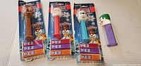front view of three sealed holiday PEZ dispensers and loose Joker