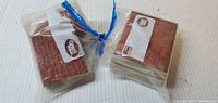 Two sealed plastic bags each containing two red rubber stamps, rubber faces visible