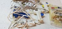All five hot glue guns with cords and bag of glue sticks on surface