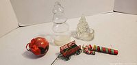 All five Christmas decorations laid out: glass tree figurine, glass tree tealight holder, metal wagon, candy cane, red ball ornament