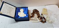 All five ornaments laid out: boxed porcelain angel, teddy bear plaque, painted wood Santa, two wrapped acrylic ornaments
