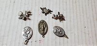 All five silver-tone charms laid out on surface