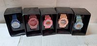 Front view of five boxed digital watches showing colours and displays
