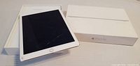 iPad Air on open retail box with lid beside