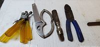 Group shot of all tools laid out: screwdrivers, opener, coupler, pliers, file