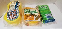 Front view of all three packaged items: car wash sponge, lawn chair re-webbing, screen spline