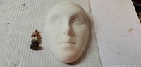 Front view of ceramic mask and miniature figure