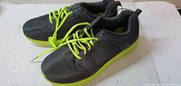 Side view of both sneakers showing grey uppers and neon green soles and laces