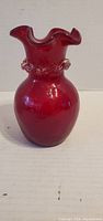 Front view of red glass vase showing ruffled rim and clear glass ring