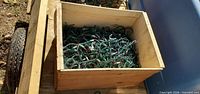 Top view of wooden crate showing tangled green-wire light strands with multi-colour bulbs