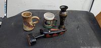Group shot of carved wood figure, two mugs, black vase