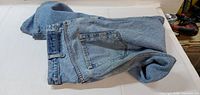 Full view of folded blue jeans showing back pocket and waistband
