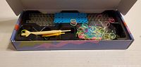 Open box displaying loom board, hook tool and multicolor bands