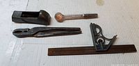 All four hand tools laid out: block plane, ratchet driver, pliers, rule with square head