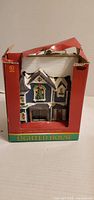 Front of boxed ceramic lighted house showing design and branding