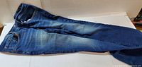 Full view of blue jeans front side showing overall condition and fade