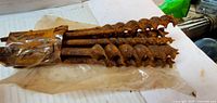 six rusted auger bits bundled together