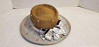 Top and front view showing straw crown, silver mesh brim, satin band, bow, studs and pearls