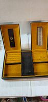 Interior view showing yellow velvet lining, ring rolls, compartments