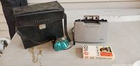 Camera, case, flash, and flashbulb box grouped on table