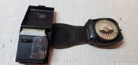 Electric razor in open plastic case next to light meter in leather case