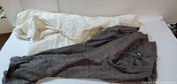 Brown knit zip-front sweater folded beside packaging