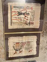 Two framed papyrus artworks, one with Egyptian figures and hieroglyphs, one with floral and bird motif