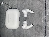 AirPods Pro left and right earbuds with closed charging case showing exterior wear