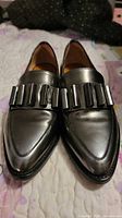 Top view of both loafers showing metallic finish and vamp ornamentation