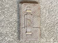 Front view of closed wallet displaying monogram canvas and gold-tone strap detail