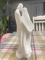Left side profile of figurine highlighting draped gown and minor chip area