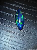 Marquise black opal on textured surface showing play-of-color