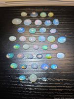 Group of loose opal cabochons laid out on dark surface