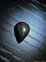 Pear cabochon black opal showing green flashes