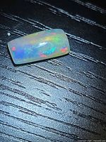 Top view of rectangular cushion cabochon opal displaying multicolored flashes