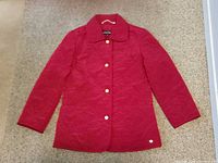 Front view of red quilted jacket with snaps and logo plate