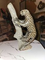 Leopard soapstone sculpture standing on tree trunk