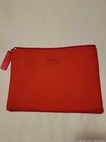 Front view of red pouch with embossed Lacoste logo