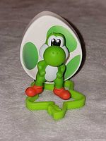 Front view of Yoshi figurine, egg disc and green clip