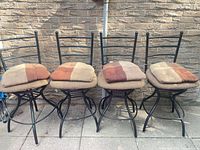 Front view of four matching metal swivel bar stools with cushions