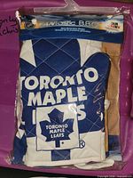 Front view of sealed package showing folded mitt and apron with Toronto Maple Leafs logo