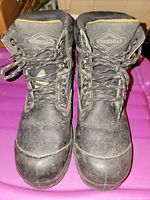 Front view of both boots showing laces, brand logo on tongue, toe condition