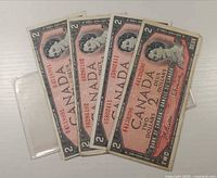 Four banknotes fanned out obverse side showing Queen portrait and serials