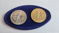 Obverse view of both coins on blue velvet insert showing female miner design and metal content text