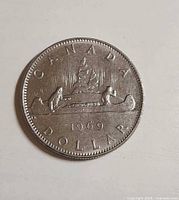 Reverse: voyageur and Indigenous person paddling canoe, date 1969 visible