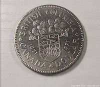 Reverse of 1971 British Columbia Centennial dollar showing shield, dogwood blossoms, legends and dates